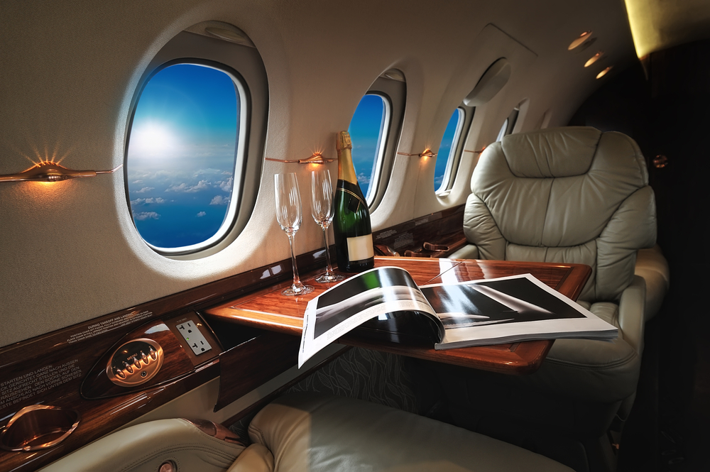 a table with wine glasses and a magazine on the side of a plane